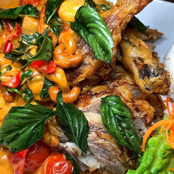 Crispy duck in red curry with cashews, basil, bell peppers, and cherry tomatoes.
