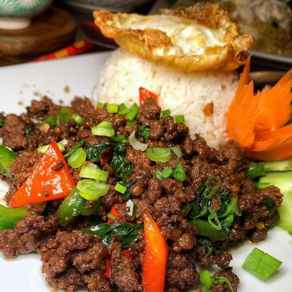 Spicy Thai basil beef with red and green peppers, scallions, rice, and a fried egg.